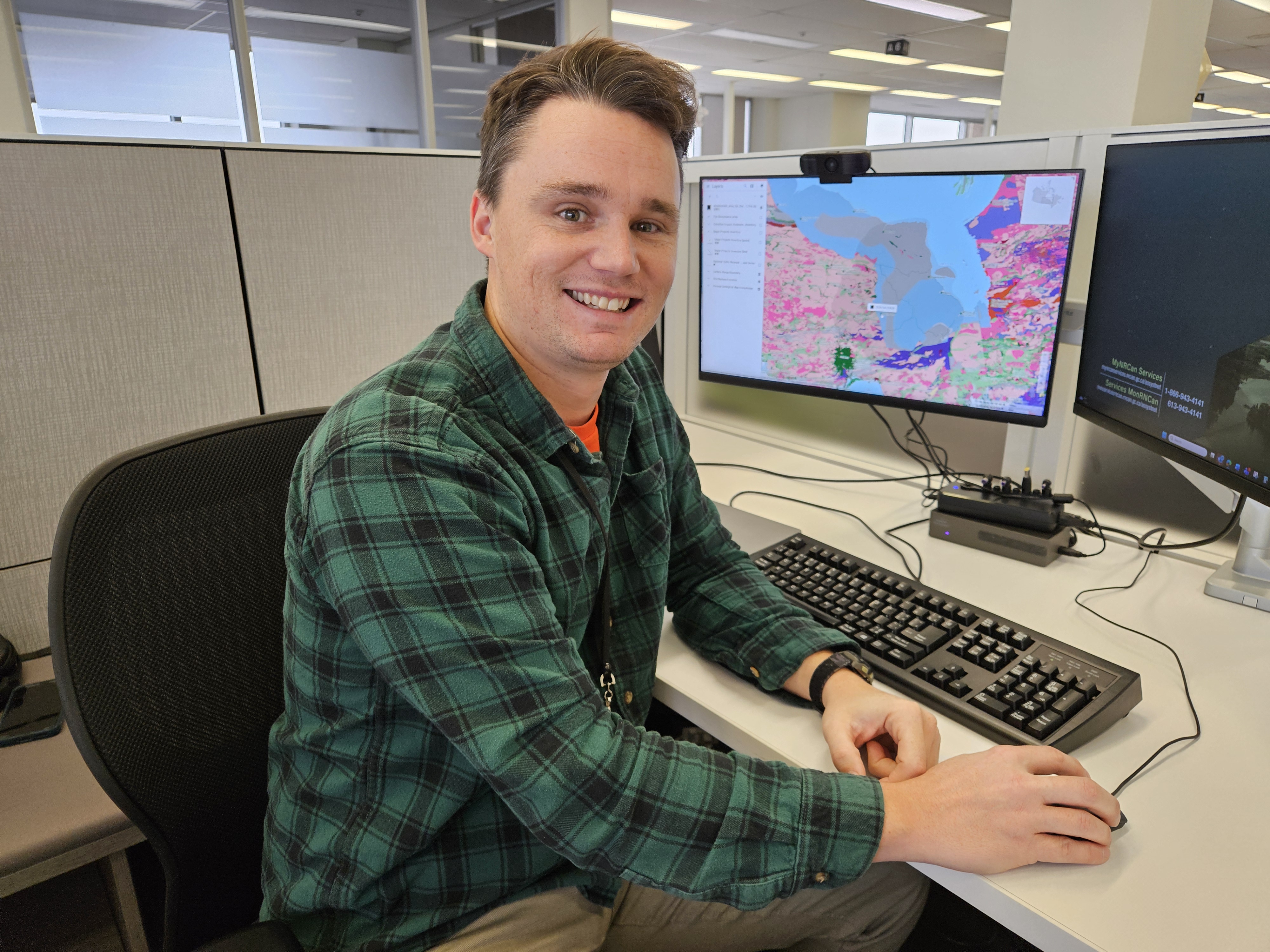 Un homme est assis à un bureau devant un écran d'ordinateur affichant une carte.